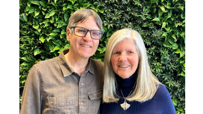 close-up photo of Peter and Nancy Torpey standing in front of a wall of foliage.